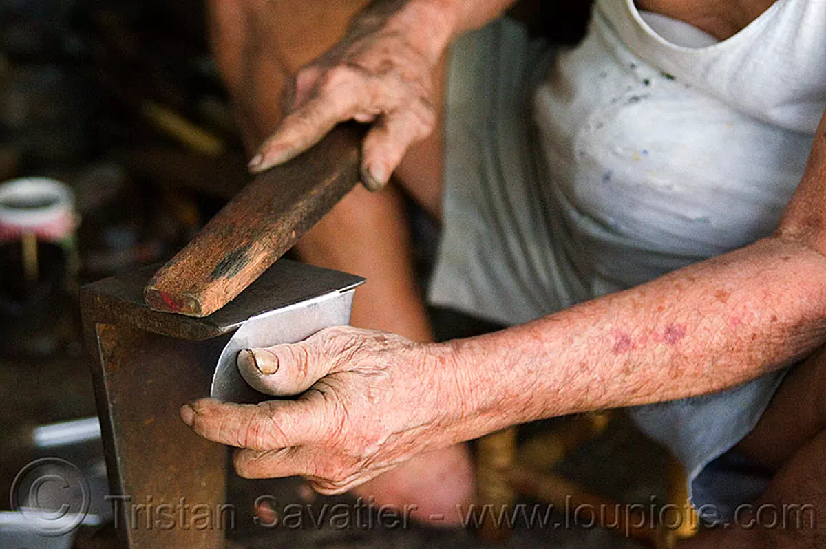 old man hammering metal plate in