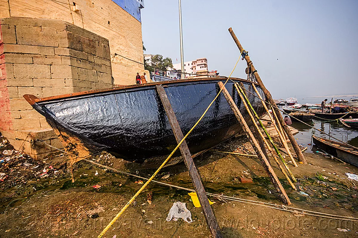 river boat with new tar coating, ghats of varanasi, india