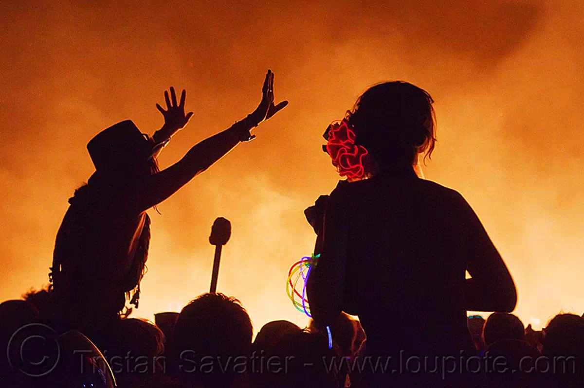 silhouettes around the man's fire - burning man 2013, backlight, burning man, celebrating, crowd, dancing, el-wire, fire, glowing, night of the burn, silhouettes