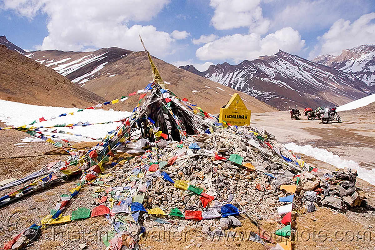 tibetan prayer flags on lachulung pass - manali to leh road (india), buddhism, india, lachulung pass, lachulungla, ladakh, motorcycle touring, motorcycles, mountain pass, mountains, prayer flags, road, royal enfield bullet, snow patches, stone cairn, tibetan