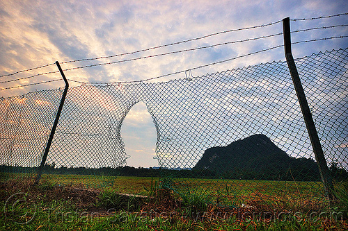 airport security perimeter breach (borneo), airport perimeter, barbwire, borneo, breach, evening, fence grid, gunung mulu national park, hole, malaysia, mulu airport, security