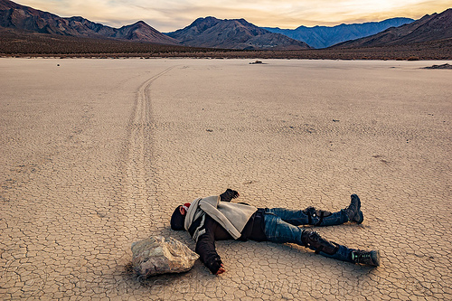 alex pretending she was hit by a sailing stone on the racetrack - death valley, cracked mud, death valley, dry lake, dry mud, landscape, laying, mountains, racetrack playa, sailing stones, sliding rocks, woman