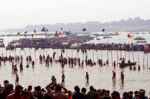 boats and hindu pilgrim bathing in the ganges river at sangam - kumbh mela 2013 (india), backlight, bathing pilgrims, colored flags, crowd, dawn, fence, ganga, ganges river, hindu pilgrimage, hinduism, holy bath, holy dip, kumbh mela, nadi bath, paush purnima, ritual bath, river bathing, river boats, silhouettes, triveni sangam