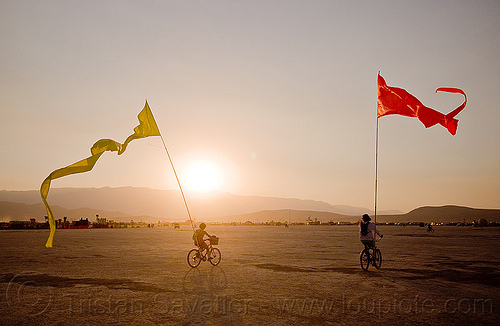 burning man - bicycles with streamer flags, bicycle flags, bicycles, poles, red, riding, streamer flags, streamers, sunset, yellow