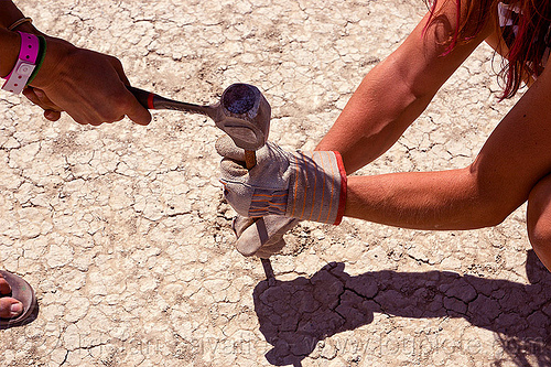 burning man - hammering a rebar, cracked mud, drought, dry mud, hammer, hammering, hands, leather gloves, rebar, sari, soil