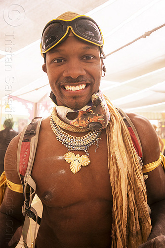 burning man - handsome man at center camp, attire, burning man outfit, goggles, metal necklaces