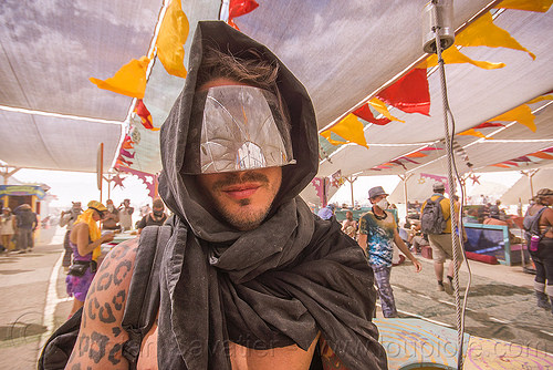 burning man - hooded man with mirror visor at center camp, arm tattoo, attire, burning man outfit, cheetah pattern tattoo, cheetah tattoo, eric flores, hood, hooded, mirror visor