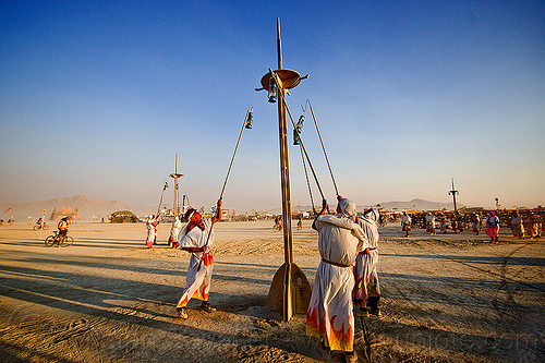 burning man - lamplighters hanging petrol lamps to light pole, lamp pole, lamplighters, light pole, petrol lanterns, poles