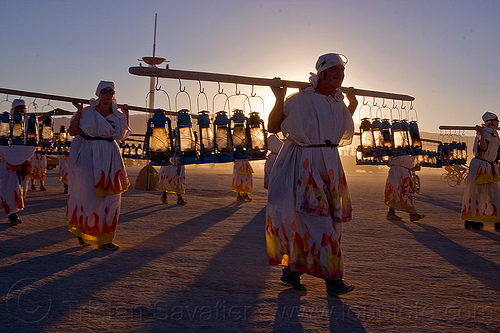 burning man - lamplighters procession at dawn, backlight, dawn, lamp lighters, lamplighter, petrol lamps, petrol lanterns, poles, sean spratt, sunset