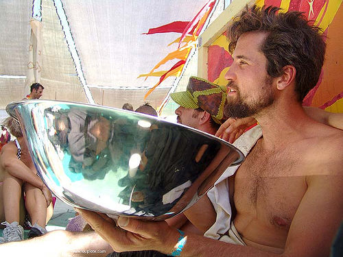 burning man - man holding large shiny metal bowl, man