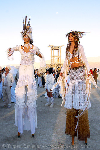 burning man - natalia and pema at the silent white procession, attire, burning man outfit, burning man temple, dawn, feathers, natalia, pema, stilt walkers, stilts, stiltwalker, stiltwalking, white morning, women