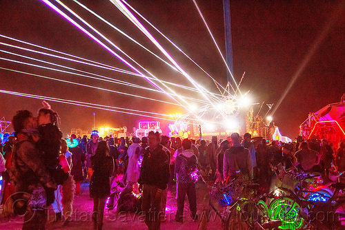 burning man - revelers dancing on the night of the burn, burning man art cars, burning man at night, dancing, mutant vehicles, unidentified art car, white lasers