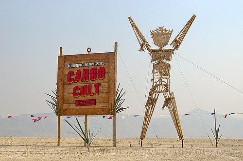 burning man - small effigy of the-man near cargo cult entrance sign, art installation, cargo cult, entrance, sculpture, sign, the man