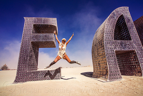 burning man - woman jumping - @ earth # home - giant letters, @earth #home, art installation, big words, jump shot, metal sculpture, steel, woman