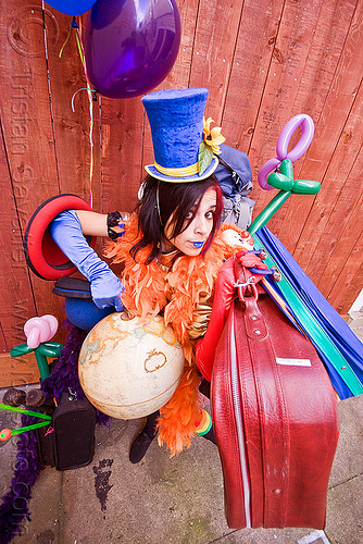 clown act - mumu circus performer, blue lipstick, bowler hat, circus artist, clown hat, cocktail hat, feather boa, globe, luggage, party balloons, performer, props, suitcases, woman