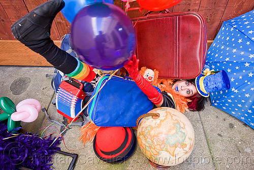 clown act - mumu circus performer, blue lipstick, bowler hat, circus artist, clown hat, cocktail hat, feather boa, globe, luggage, party balloons, performer, props, suitcases, woman