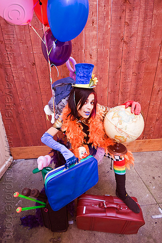 clown act - mumu circus performer, blue lipstick, circus artist, clown hat, cocktail hat, feather boa, globe, luggage, party balloons, performer, props, suitcases, woman