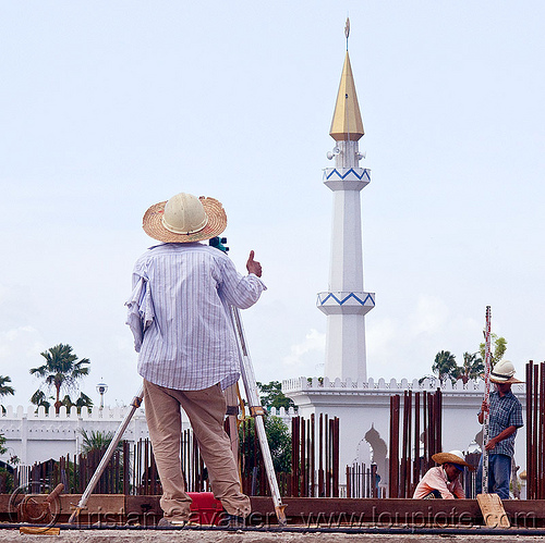 construction surveying - theodolite and tower ruler, borneo, building construction, construction site, construction surveying, construction surveyor, construction workers, geometer, islam, malaysia, man, minaret, miri, mosque, safety helmet, standing, straw hat, sun hat, survey, theodolite, thumb up, tower ruler, tripod