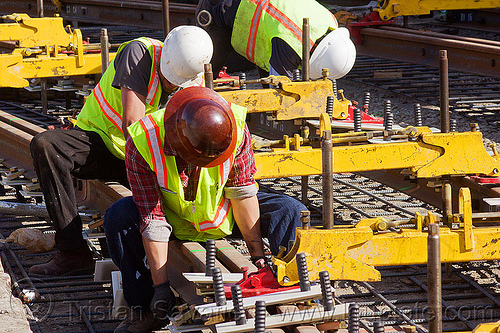 construction workers bolting railroad ties to new tracks, construction workers, duboce, high-visibility jacket, high-visibility vest, light rail, men, muni, ntk, rail jacks, railroad construction, railroad tracks, railway tracks, reflective jacket, reflective vest, safety helmet, safety vest, san francisco municipal railway, track jacks, track maintenance, track work, working