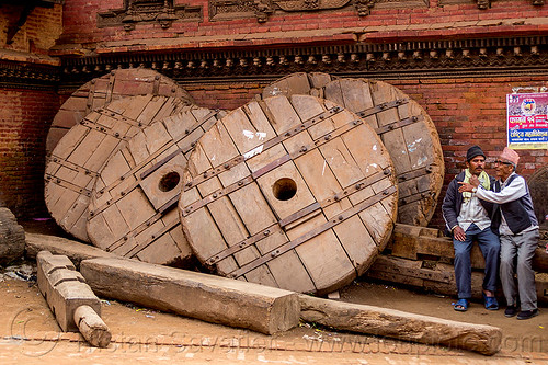 giant wooden wheel of the bhairab chariot used during the bisket jatra festival - bhaktapur  (nepal), bhaktapur, men, standing, tachupal tole, wooden wheels