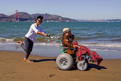 grandma on beach wheelchair with granddaughter running on the beach, beach wheelchair, blanket, chinese woman, crissy field beach, family, grandma, grandmother, jenn, old woman, rolling, sand, senior, straw hat, women