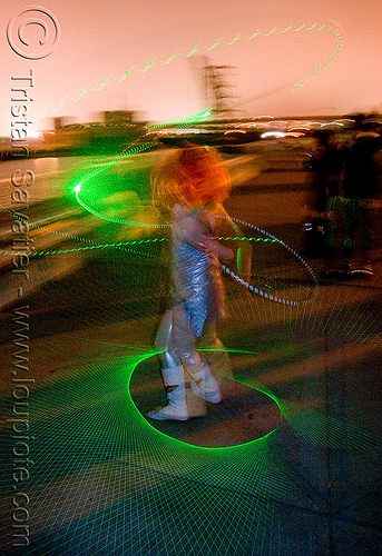 green laser hula hoop light patterns, green laser, islais creek promenade, laser hoop, laser hula hoop, night, superhero street fair, woman