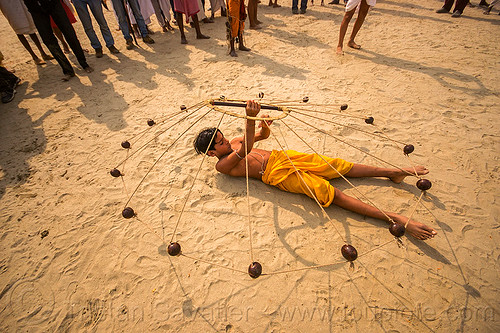 hindu boy spinning balls with ropes (india), boy, game, hindu pilgrimage, hinduism, indian spinning balls, kumbh mela, laying down, metal balls, performer, ropes