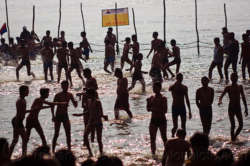hindu boys running and dancing in the ganges river at sangam - kumbh mela 2013 (india), backlight, boys, crowd, dancing, dawn, fence, ganga, ganges river, hindu pilgrimage, hinduism, holy bath, holy dip, india, maha kumbh mela, men, nadi bath, paush purnima, pilgrims, ritual bath, river bathing, river boats, running, silhouettes, triveni sangam