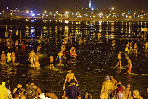 hindu pilgrims bathing in the ganges river at sangam at night - kumbh mela 2013 (india), bathing pilgrims, crowd, fence, ganga, ganges river, hindu pilgrimage, hinduism, holy bath, holy dip, kumbh mela, men, nadi bath, night, paush purnima, ritual bath, river bathing, street lights, triveni sangam, women