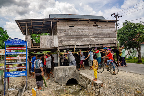 house moving - people carry a house to a new location, crowd, house relocation, men, road, structure relocation, village