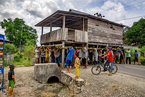 house moving - people lift and carry an entire house to a new location, crowd, house relocation, men, road, structure relocation, village