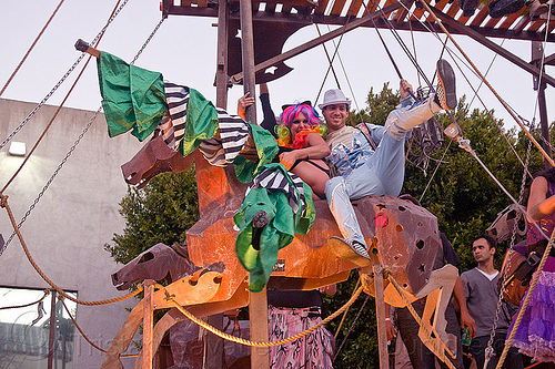 kicking leg up, a cavallo, horse carousel, man, metal horse, riding, stilter, woman