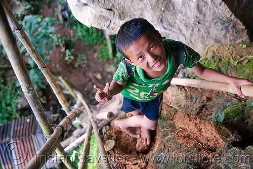 kid on bamboo ladder to cliff cave near vang vieng (laos), bamboo ladder, boy, caving, child, cliff, guide, kid, natural cave, peace sign, spelunking, v-sign, vang vieng, victory sign