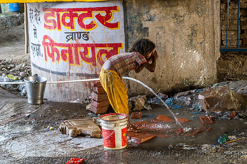 little girl washing face at water hose, bridge pillar, child, daraganj, hindu pilgrimage, hinduism, kid, kumbh mela, little girl, metal bucket, plastic pipe, plastic piping, steel bucket, washing, water hose, water pipe