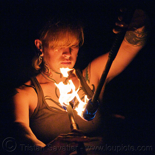 looking at her fire staves - leah, fire dancer, fire dancing, fire performer, fire spinning, fire staffs, fire staves, leah, night, tattooed, tattoos, woman