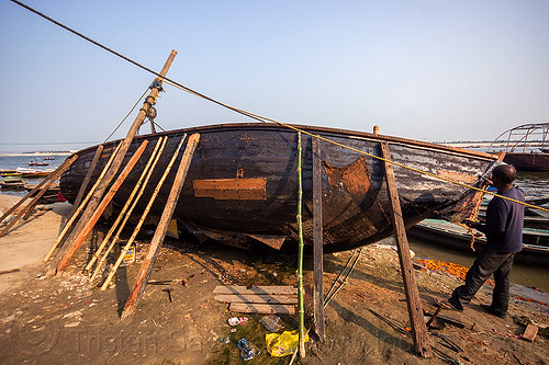 man fixing old wooden riverboat (india), fixing, ganga, ganges river, ghats, hull, man, repairing, river bank, river boat, sticks, tar, varanasi