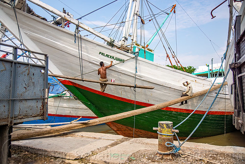 man on suspended scaffold repainting pinisi boat - traditional wooden cargo boat, boats, bugis schooners, dock, harbor, man, painting, palaekajuara, pinisi, ships, surabaya, suspended scaffold