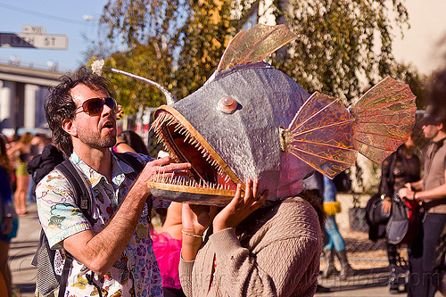 man wearing a fish mask with sharp teeth, fish mask, man, woman