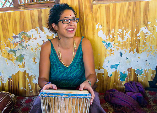 maryam with djembe drum, bindi, bracelets, djembe drum, drummer, eyeglasses, eyewear, maryam, musical instrument, necklaces, peeling paint, percussion, prescription glasses, rishikesh, sitting, spectacles, woman