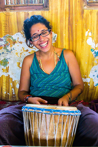 maryam with djembe drum, bindi, bracelets, djembe drum, drummer, eyeglasses, eyewear, maryam, musical instrument, necklaces, peeling paint, percussion, prescription glasses, rishikesh, sitting, spectacles, woman