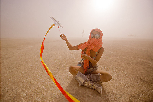 mini-kite, boots, cross-legged, dust storm, flying, goggles, haboob, minah, mini kite, orange scarf, playa dust, red, sitting, streamers, string, whiteout, wind, woman, yellow