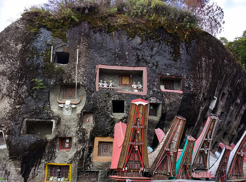 miniature tongkonan structures in front of wall of toraja rock-tombs - lembang tonga riu - lo'ko mata wall, boulder, burial site, cemetery, graves, graveyard, lembang tonga riu, liang pak, lo'ko mata wall, miniature tongkonan, pa'tedong, rock tombs, tana toraja, tongkonan roof