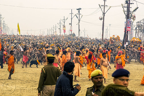 naga babas procession at the kumbh mela (india), cops, crowd, flower necklaces, hindu pilgrimage, hinduism, holy ash, kumbh mela, marigold flowers, men, naga babas, naga sadhus, police officers, sacred ash, sadhu, triveni sangam, vasant panchami snan, vibhuti, walking