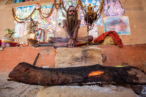 naga sadhu and his camp fire in varanasi (india), baba, beard, campfire, cross-legged, damaru drum, dreadlocks, ghats, hindu ritual drum, hinduism, man, naga babas, naga sadhus, posters, sadhu, sitting, tree log, varanasi, wood