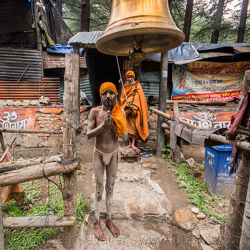 naga sadhu under large bell on gangotri road (india), baba, bell, bhagirathi valley, bhagwa, brass, hinduism, holy ash, india, men, naga babas, naga sadhus, sacred ash, sadhu, saffron color, standing, test1, vibhuti