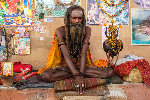 naked baba - naga sadhu sitting crosslegged in varanasi (india), baba, beard, bracelets, cross-legged, damaru drum, dreadlocks, finger rings, ghats, hindu man, hindu ritual drum, hinduism, naga babas, naga sadhus, necklaces, posters, sadhu, sitting, tilak, tilaka, trident, varanasi