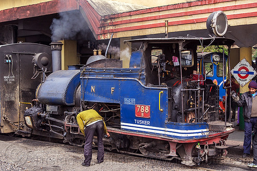 operator inspecting the rods of a steam locomotive at the darjeeling train station (india), 788 tusker, darjeeling himalayan railway, darjeeling toy train, men, narrow gauge, railroad, smoke, smoking, steam engine, steam locomotive, steam train engine, train car, train station, worker, working