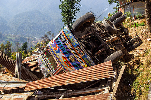 overturned truck crashed on house roof (nepal), corrugated metal, crash, ditch, lorry accident, mountain road, overturned, rollover, tata motors, traffic accident, truck accident, up-side-down, wreck