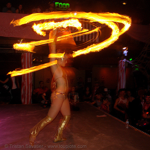 performer spinning fire hula hoop - indoor (san francisco), bohemian carnival, fire dancer, fire dancing, fire hula hoop, fire performer, fire spinning, hula hooping, indoor, night, spinning fire, woman