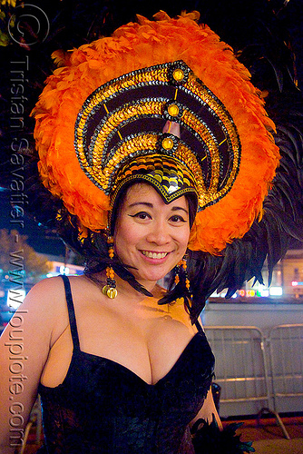 pretty asian woman in costume with large feather hat - halloween in the castro (san francisco), asian woman, costume, feather hat, feathers, halloween, night, orange